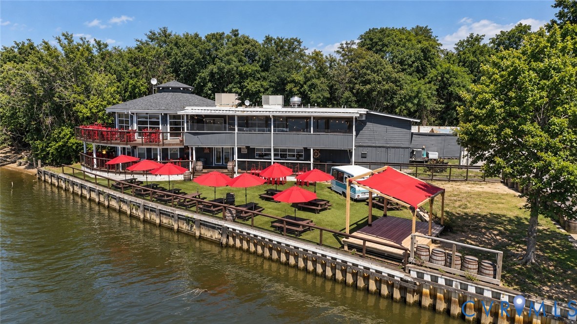 Waterfront property featuring a bulkhead, expansive lawn, multi-level exterior decking, and a covered wooden structure