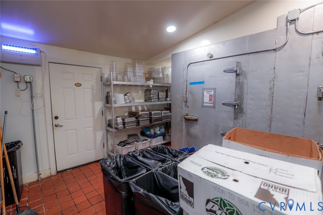 Walk-in industrial freezer unit, recessed ceiling lighting, metal shelving, and tile flooring