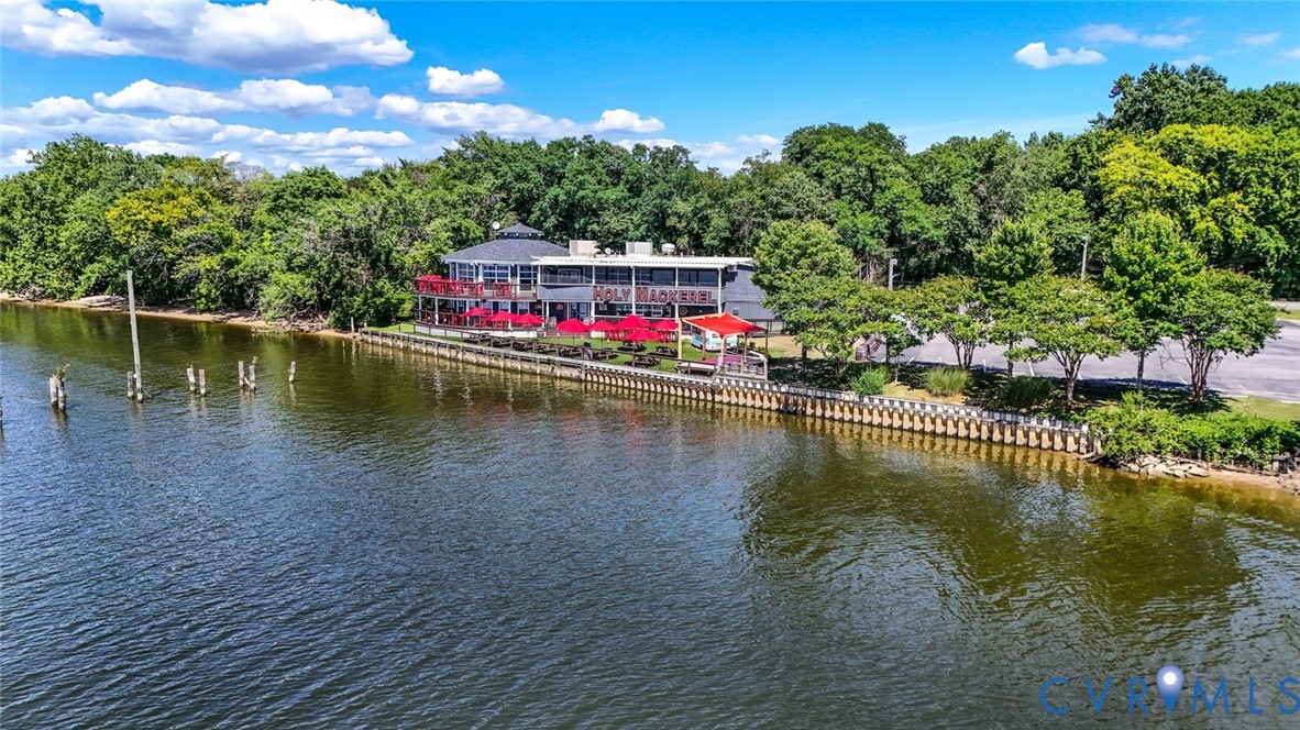 Waterfront commercial property featuring bulkheaded shoreline, multi-level building architecture, expansive paved parking area, and mature perimeter landscaping
