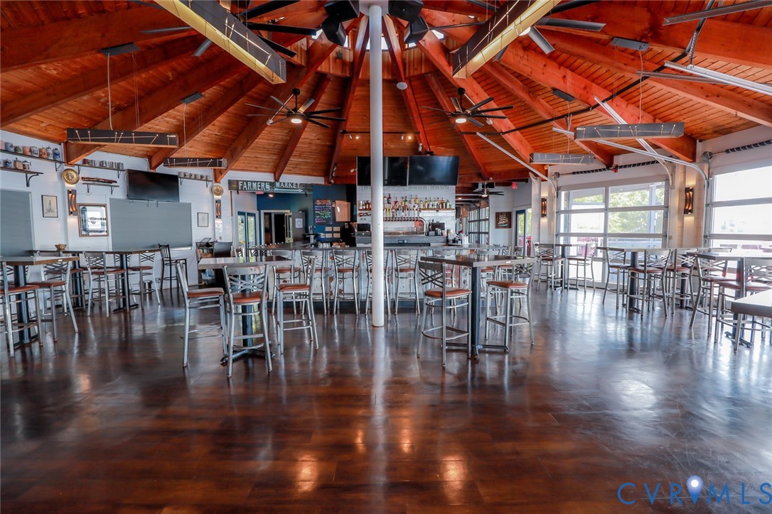 Expansive circular interior featuring a vaulted wood-beam ceiling, high-gloss polished concrete flooring, multiple ceiling fans, and overhead glass-paneled garage-style doors