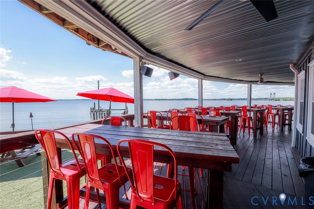 Covered waterfront patio featuring wood decking, a metal ceiling, and cable railing