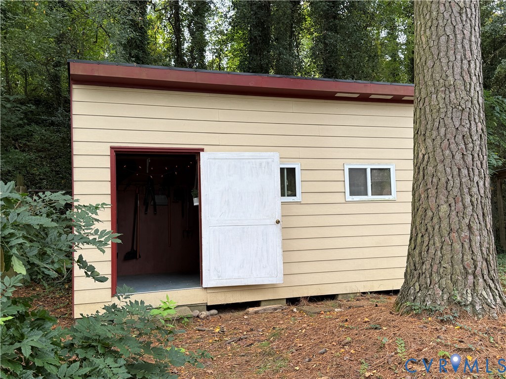Detached structure featuring horizontal lap siding, a shed roof, two rectangular sliding windows, and a swinging entrance door Detached structure featuring horizontal lap siding, a shed roof, two rectangular sliding windows, and a swinging entrance door