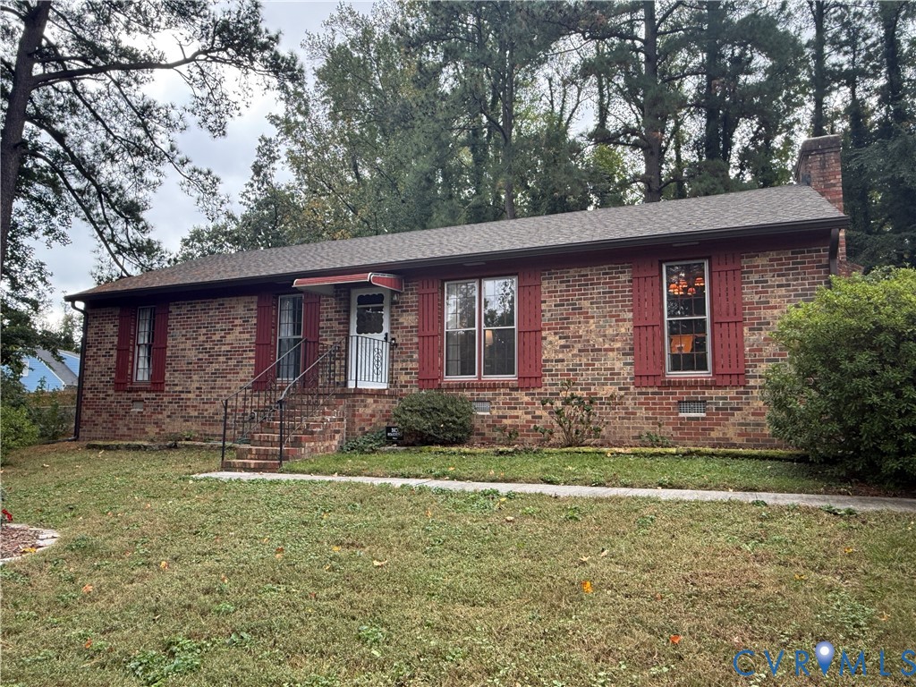 Brick exterior featuring red shutters, a gable roof, a brick chimney, and a metal-railed entrance Brick exterior featuring red shutters, a gable roof, a brick chimney, and a metal-railed entrance