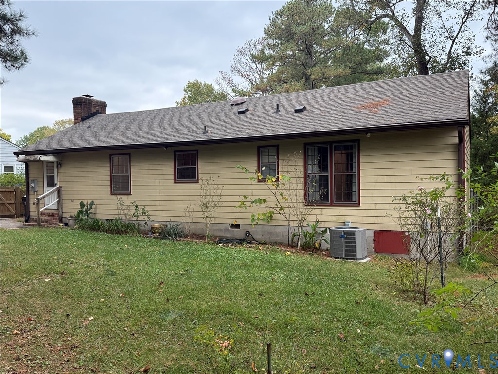 Exterior rear elevation featuring horizontal lap siding, a pitched asphalt shingle roof, a masonry chimney, and established perimeter landscaping Exterior rear elevation featuring horizontal lap siding, a pitched asphalt shingle roof, a masonry chimney, and established perimeter landscaping