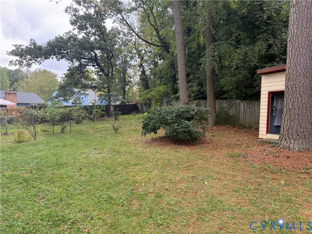 Expansive rear grounds featuring mature trees, wood fencing, and a detached storage structure Expansive rear grounds featuring mature trees, wood fencing, and a detached storage structure