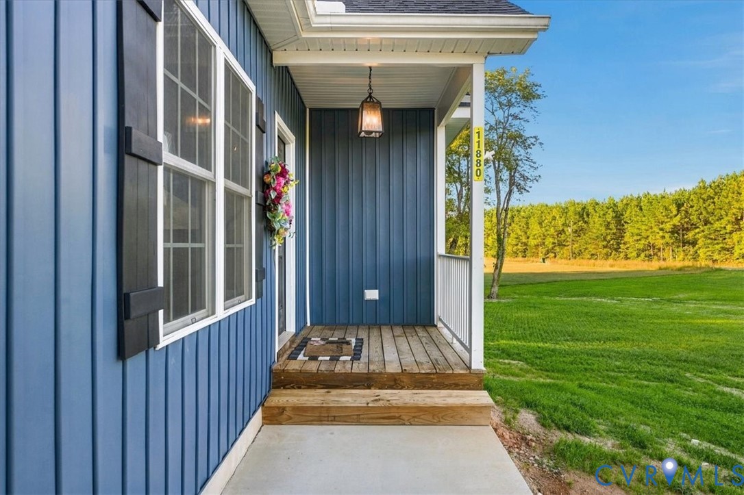 Covered entryway with vertical blue siding, wood-plank decking, attached hanging light fixture, and contrasting black shutters Covered entryway with vertical blue siding, wood-plank decking, attached hanging light fixture, and contrasting black shutters