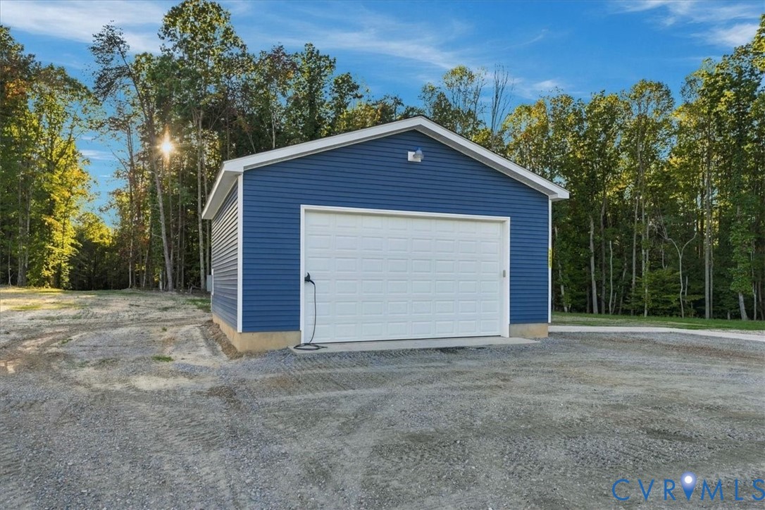 Expansive outdoor space featuring a paved concrete landing, gravel hardscaping, and mature trees