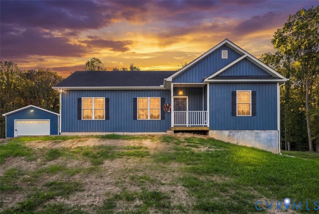 Single-story residence featuring blue vertical siding, dark shutters, a covered front porch with white railing, and a detached one-car garage Single-story residence featuring blue vertical siding, dark shutters, a covered front porch with white railing, and a detached one-car garage