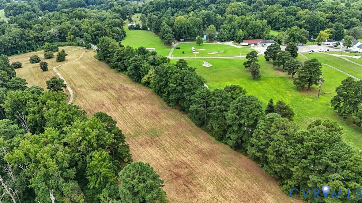 Expansive acreage featuring mature tree lines, open meadow terrain, and paved pathways