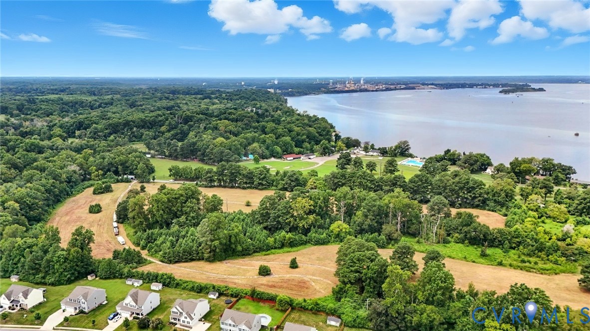 Aerial perspective featuring expansive acreage, mature tree clusters, and direct water frontage Aerial perspective featuring expansive acreage, mature tree clusters, and direct water frontage