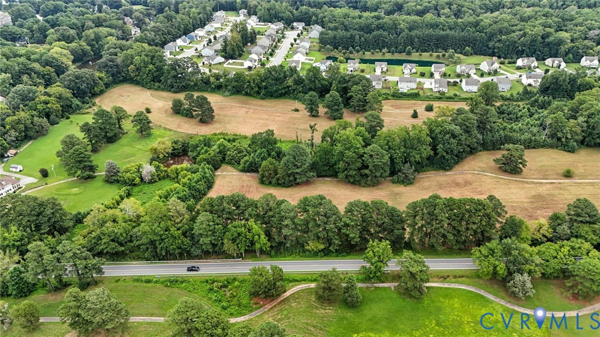 Expansive parcel of land featuring mature trees, open grassy areas, and a multi-use paved path