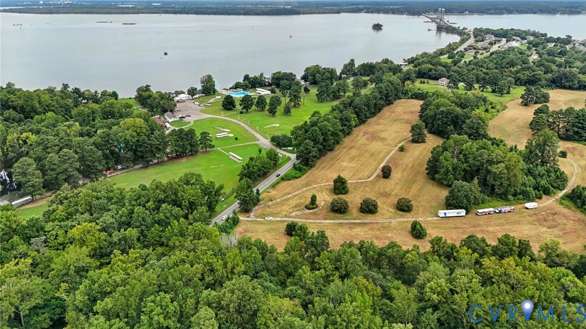 Aerial perspective featuring expansive acreage, mature tree clusters, open grass fields, and proximity to the shoreline