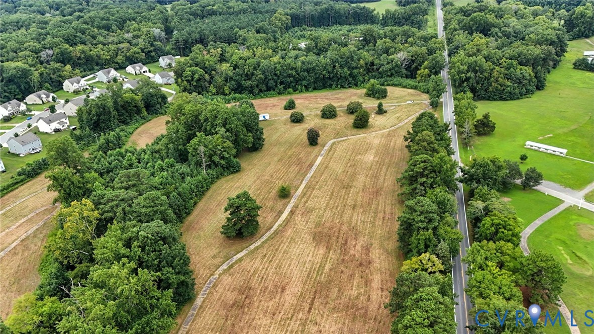 Expansive parcel of land featuring cleared acreage, mature tree borders, and paved road access