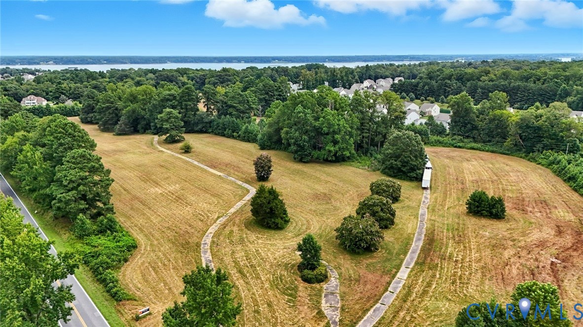 Expansive acreage featuring mature trees, concrete pathways, and surrounding natural greenery