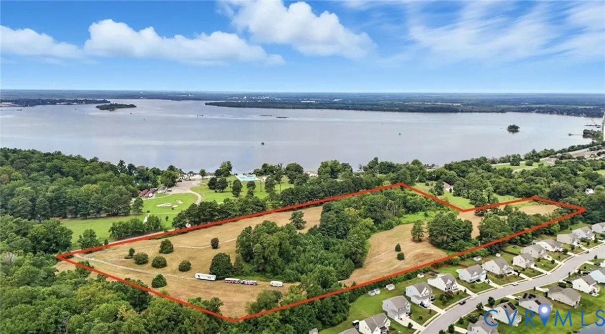 Aerial view of expansive, cleared land featuring mature trees and direct proximity to the waterfront Aerial view of expansive, cleared land featuring mature trees and direct proximity to the waterfront
