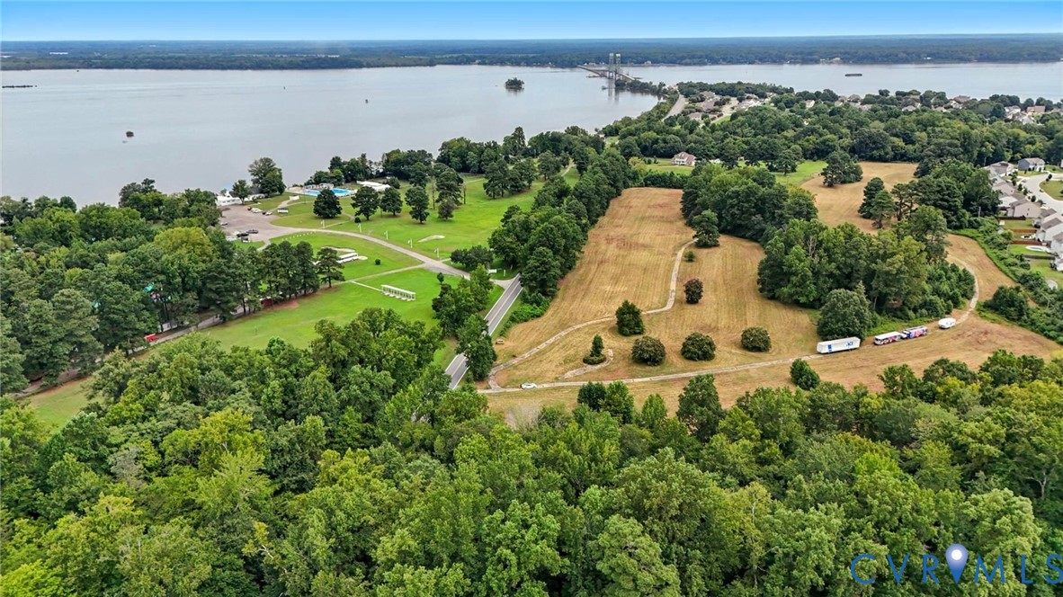 Aerial perspective of expansive acreage featuring mature woodland, open grassy meadows, and prominent water frontage