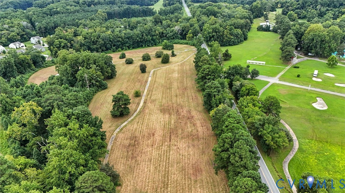 Expansive cleared parcel featuring mature tree buffers, defined perimeter boundaries, and direct access to an asphalt paved road