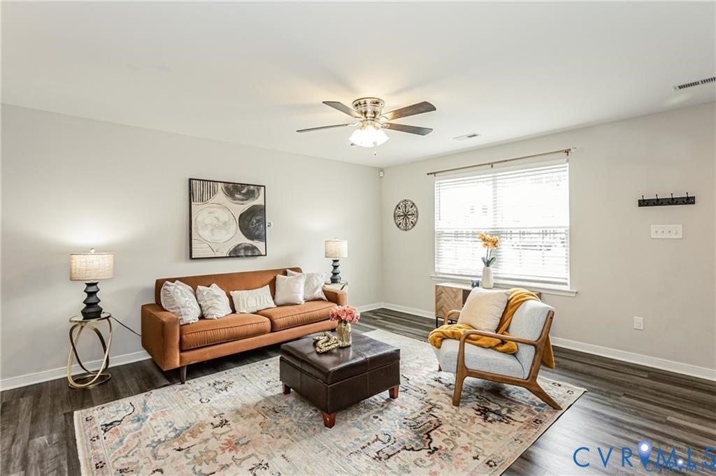Living space featuring wood-finish flooring, neutral wall paint, and a central ceiling fan with integrated lighting