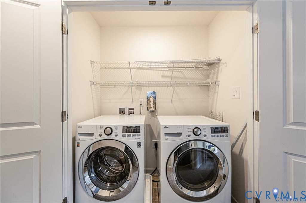 Laundry closet featuring dual white front-load appliances and tiered white wire shelving