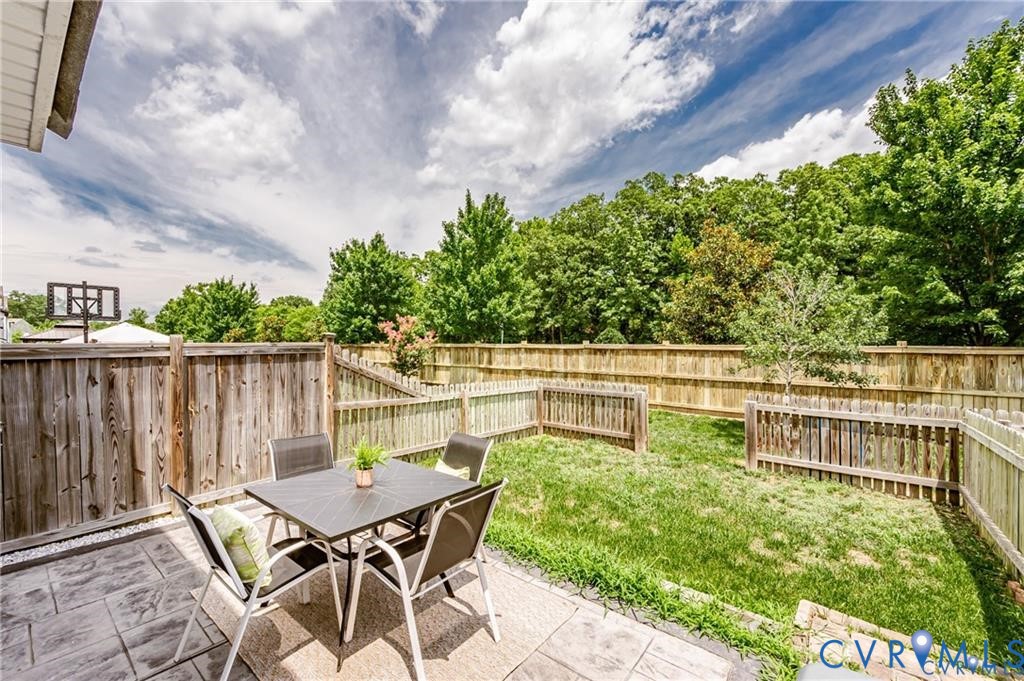 Rear yard featuring a stamped concrete patio, wood privacy fencing, and a grass lawn