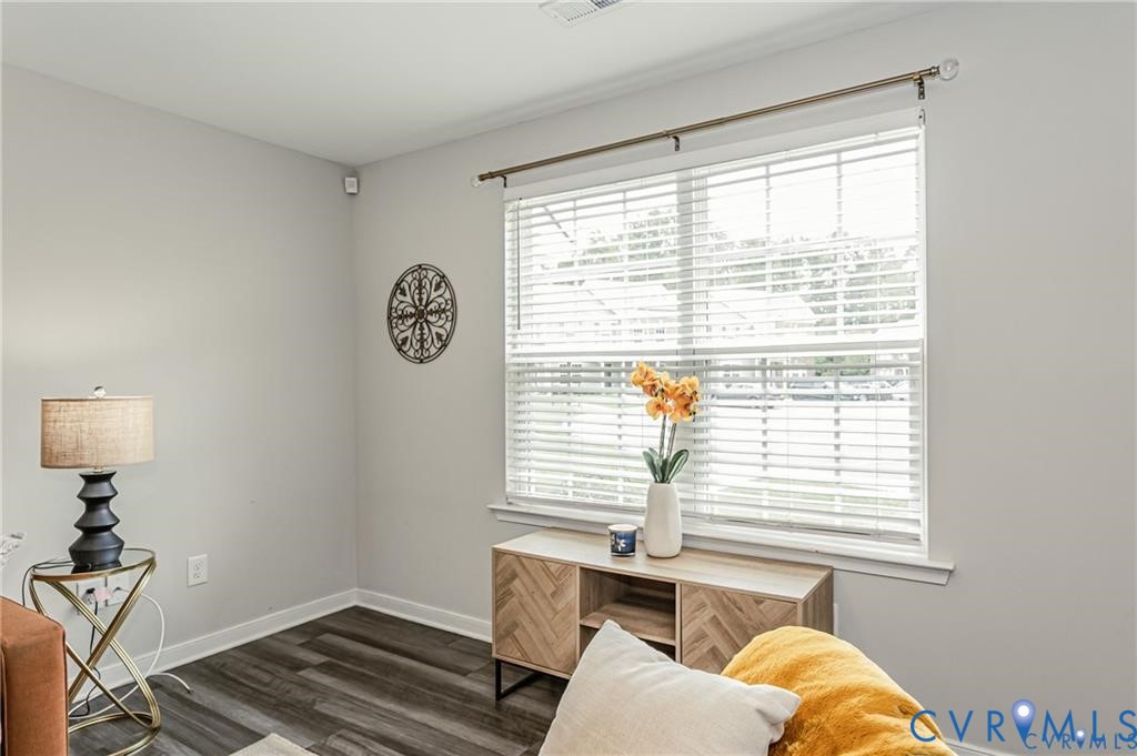 Wood-finish flooring, neutral wall tones, and a multi-pane window featuring installed horizontal blinds and a metal curtain rod