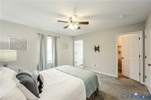 Neutral-toned room featuring wall-to-wall carpeting, a multi-blade ceiling fan with integrated lighting, and multiple panel doors
