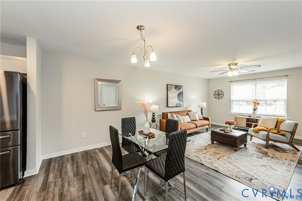 Open-concept living space featuring wood-finish flooring, a multi-bulb chandelier, a ceiling fan with integrated lighting, and neutral wall paint