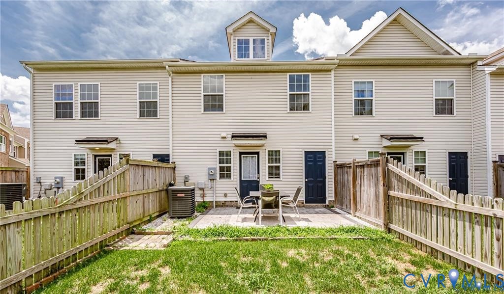 Light-colored siding exterior with a shingled roof, featuring a private fenced-in yard and a paved patio area