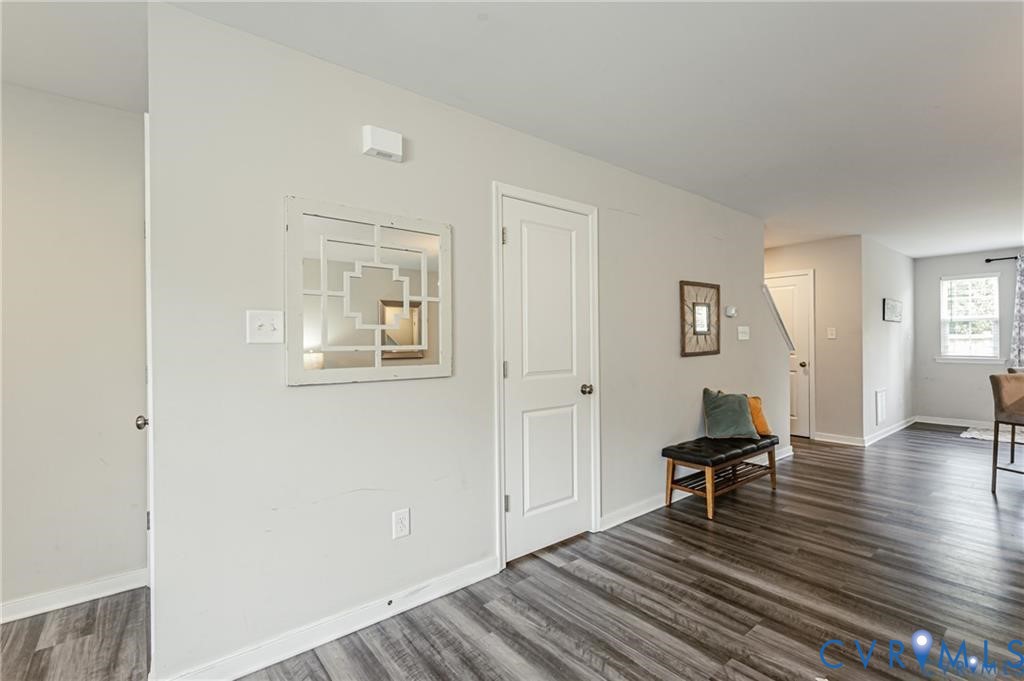 Wood-finish flooring, neutral wall tones, multi-panel interior door, and window with natural light