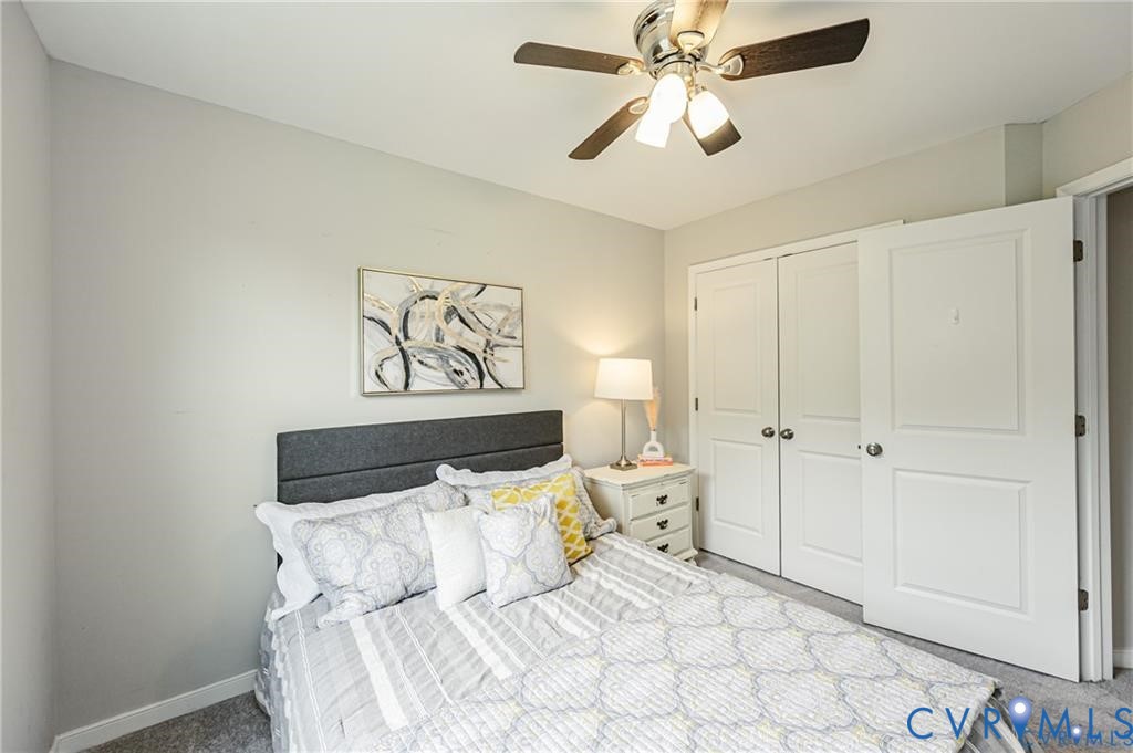 Neutral-toned interior featuring carpeted flooring, a ceiling fan with integrated lighting, and a dual-panel closet door
