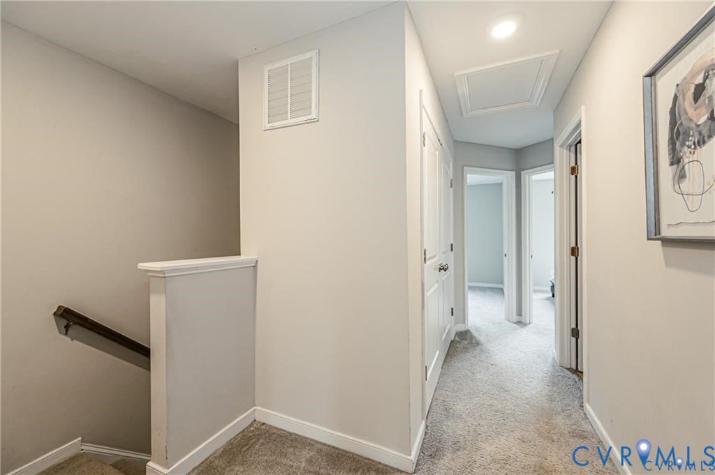 Hallway featuring neutral wall paint, carpeted flooring, two-panel interior doors, and recessed lighting