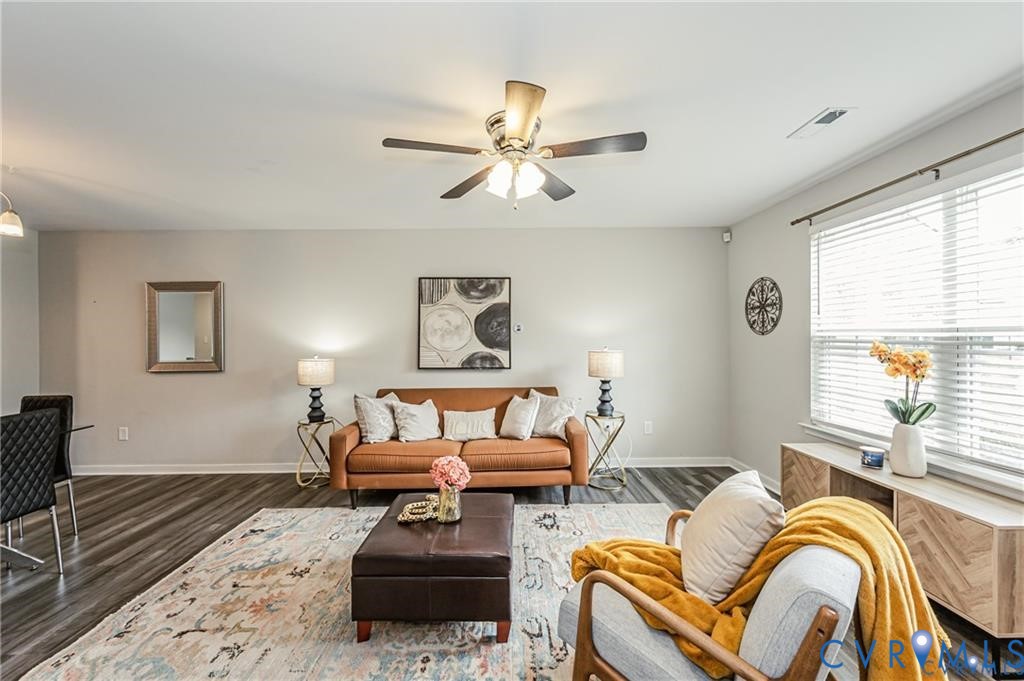 Living area featuring wood-finish flooring, a ceiling fan with integrated lighting, and horizontal window blinds