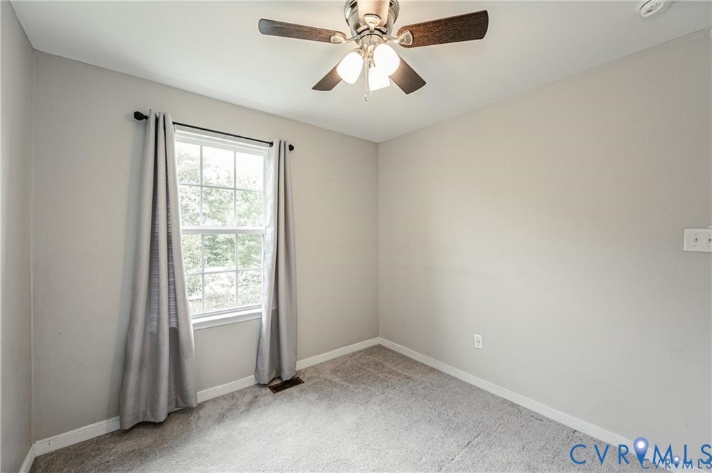 Neutral-toned walls, wall-to-wall carpeting, multi-pane window with natural light, and a ceiling-mounted light fixture with a fan