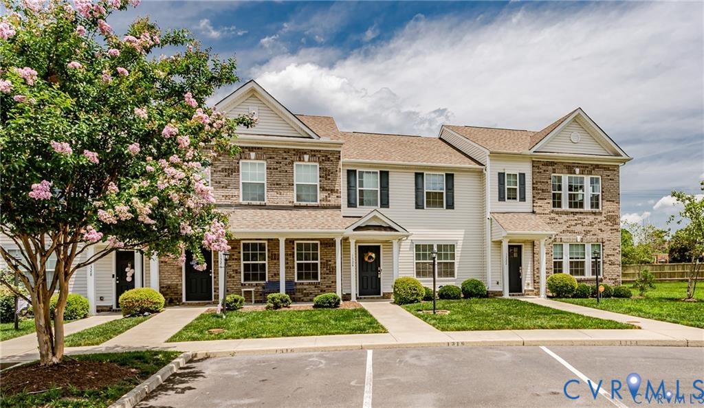 Multi-unit residence featuring a brick and vinyl siding exterior, asphalt shingle roof, covered front porches, and manicured lawn