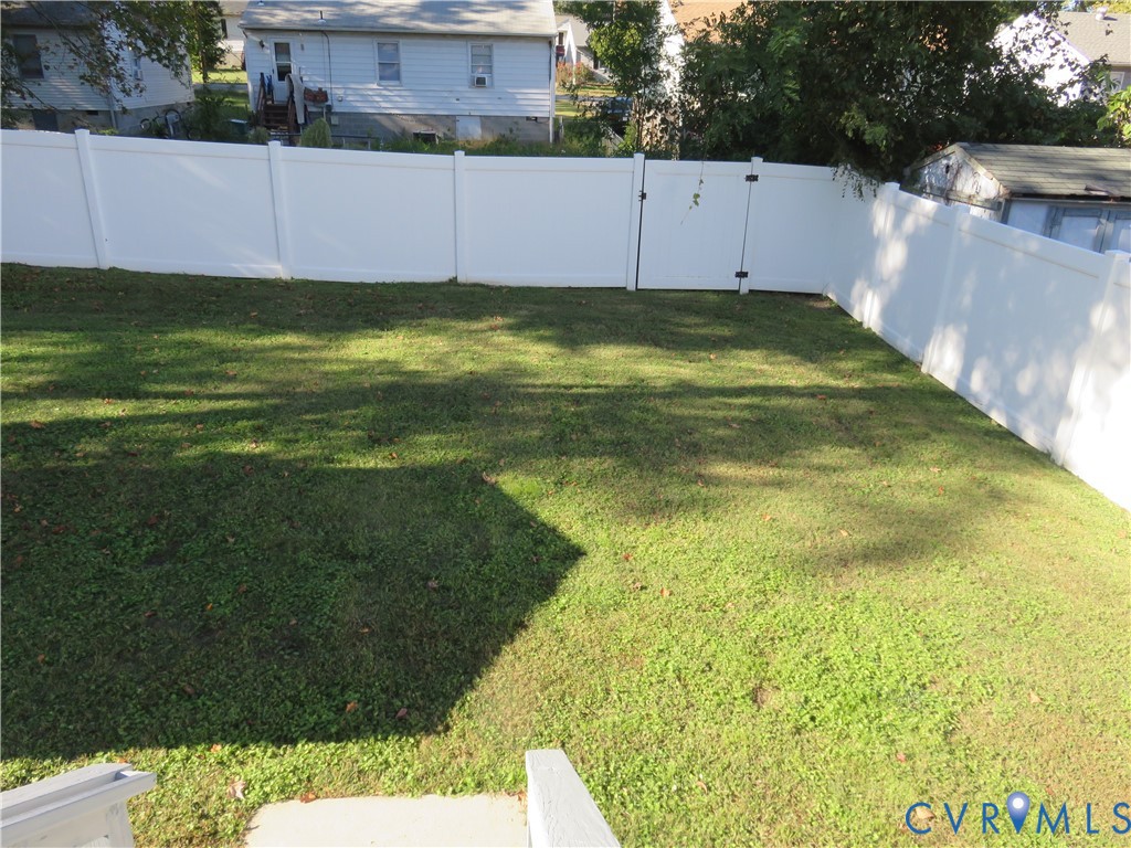 Rear yard enclosed by white vinyl fencing and featuring an open lawn area