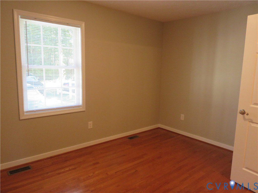 Interior room featuring wood-finish flooring, neutral wall paint, and a single-pane window with white trim