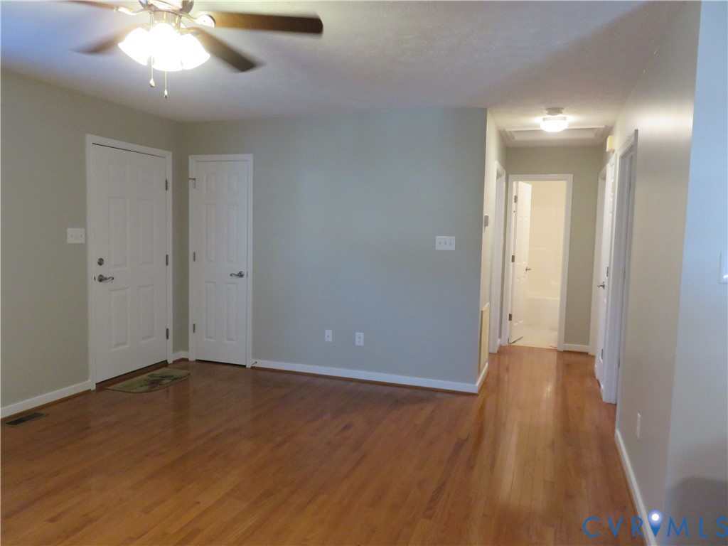 Wood-finish flooring, ceiling fan with integrated lighting, multi-panel doors, and neutral wall tones