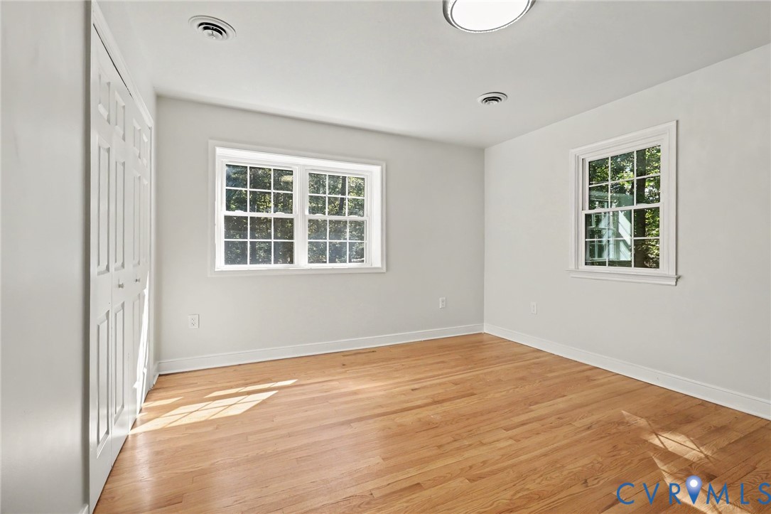 Neutral-toned interior featuring wood-finish flooring, multi-pane windows, and double-door closet cabinetry