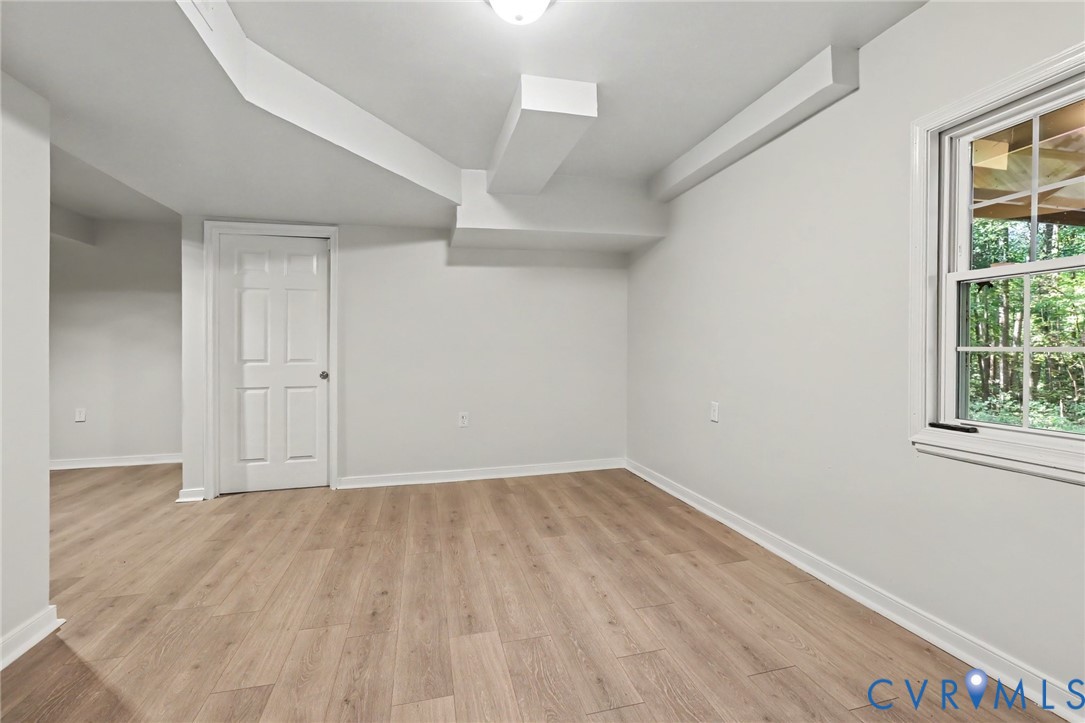 Room interior featuring wood-finish flooring, a single-hung window, and a multi-panel interior door