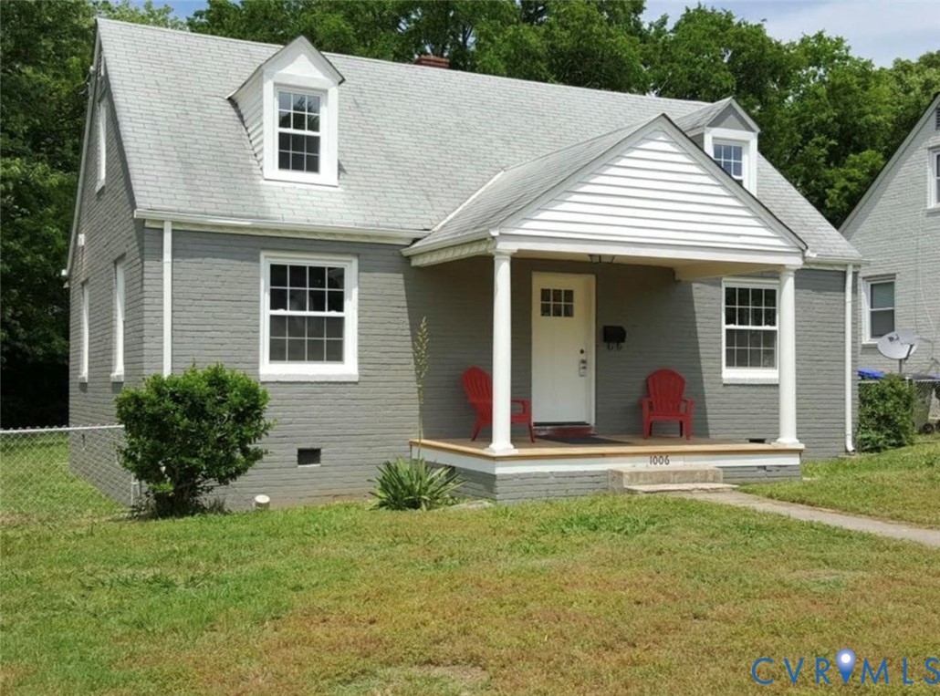 Cape Cod exterior featuring a painted brick facade, covered front porch with column supports, and two dormer windows Cape Cod exterior featuring a painted brick facade, covered front porch with column supports, and two dormer windows
