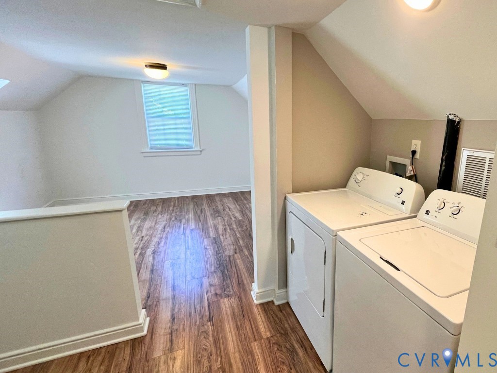 Wood-finish flooring, vaulted ceilings, and a dedicated laundry area featuring integrated hookups and flush-mount lighting