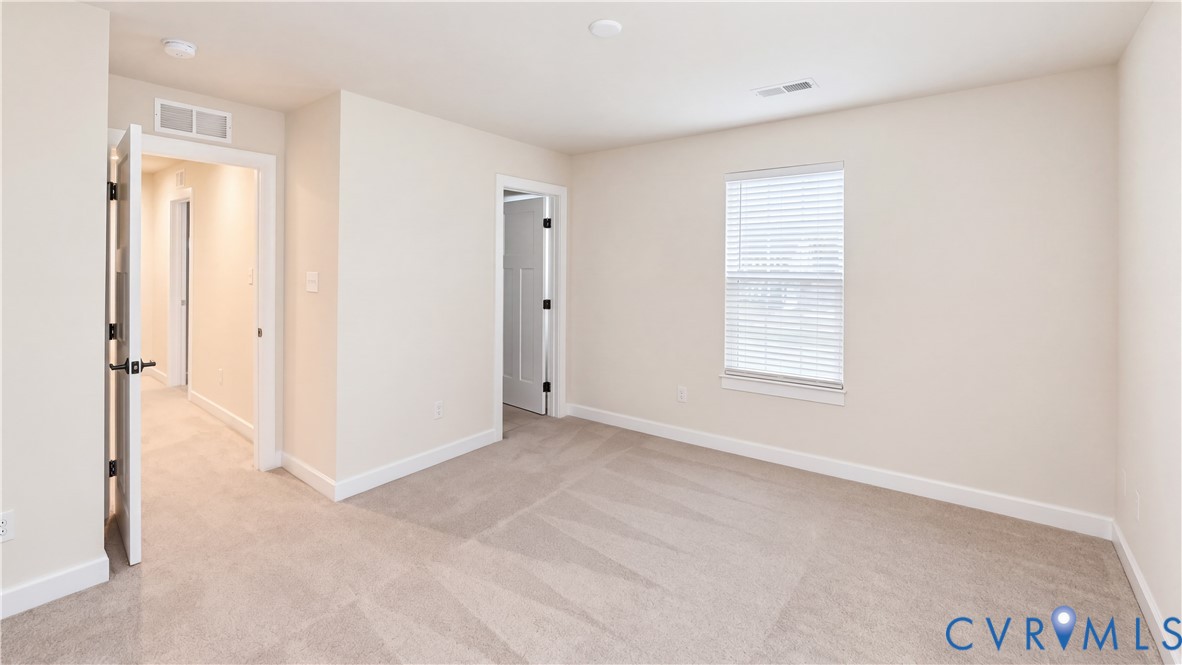Neutral interior room with plush wall-to-wall carpeting, crisp off-white walls, white trim detailing, and a double-hung window featuring built-in blinds