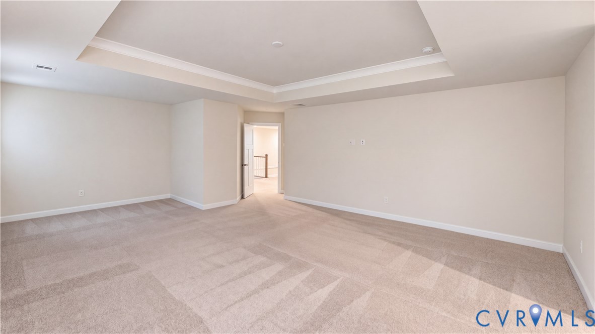 Spacious interior room featuring a tray ceiling, neutral wall tones, and wall-to-wall carpeting