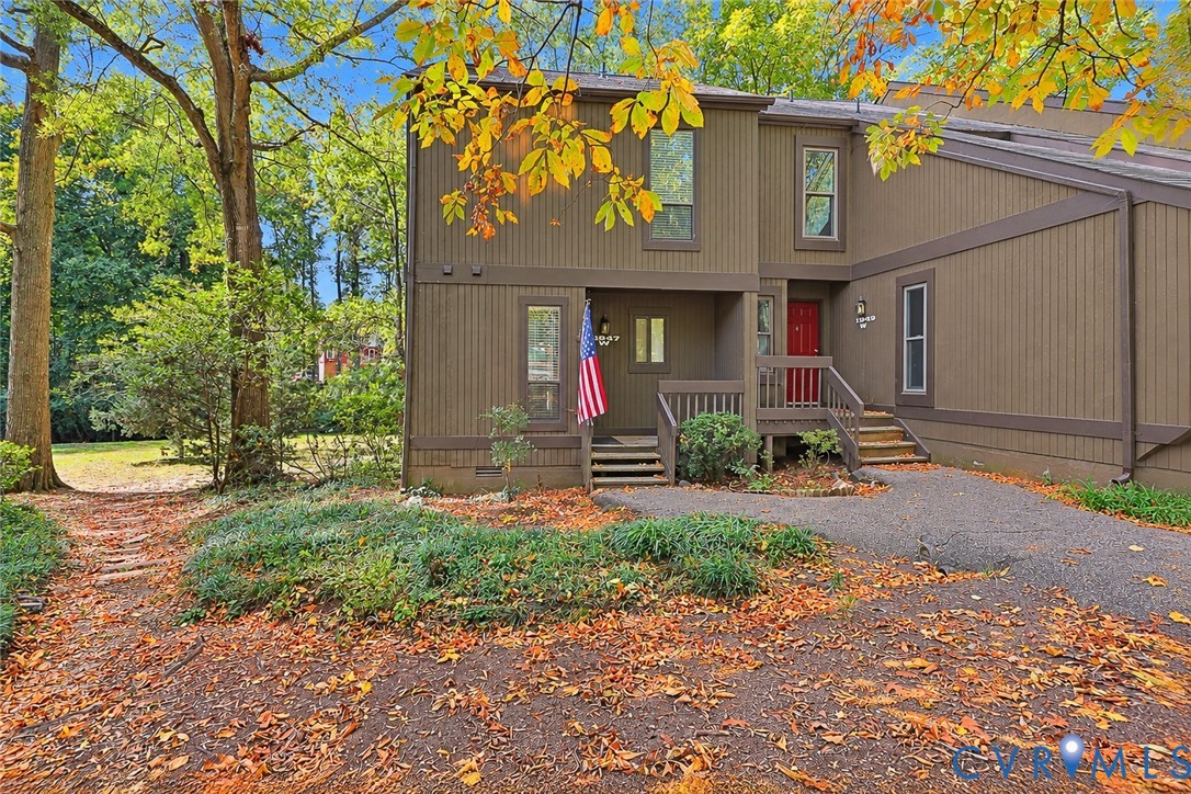 Vertical wood siding exterior featuring a multi-level design, elevated wooden entry staircase, and mature tree landscaping