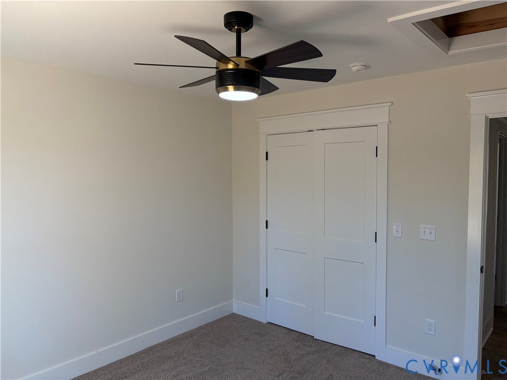 Modern six-blade ceiling fan with integrated LED lighting, white double-panel closet doors, and neutral wall-to-wall carpeting