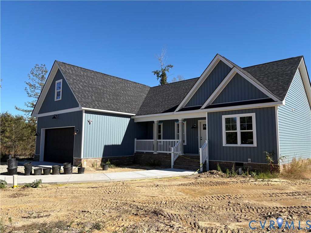 Blue vertical siding exterior featuring a multi-gabled roofline, stone veneer foundation, covered front porch with a white railing, and an attached two-car garage Blue vertical siding exterior featuring a multi-gabled roofline, stone veneer foundation, covered front porch with a white railing, and an attached two-car garage