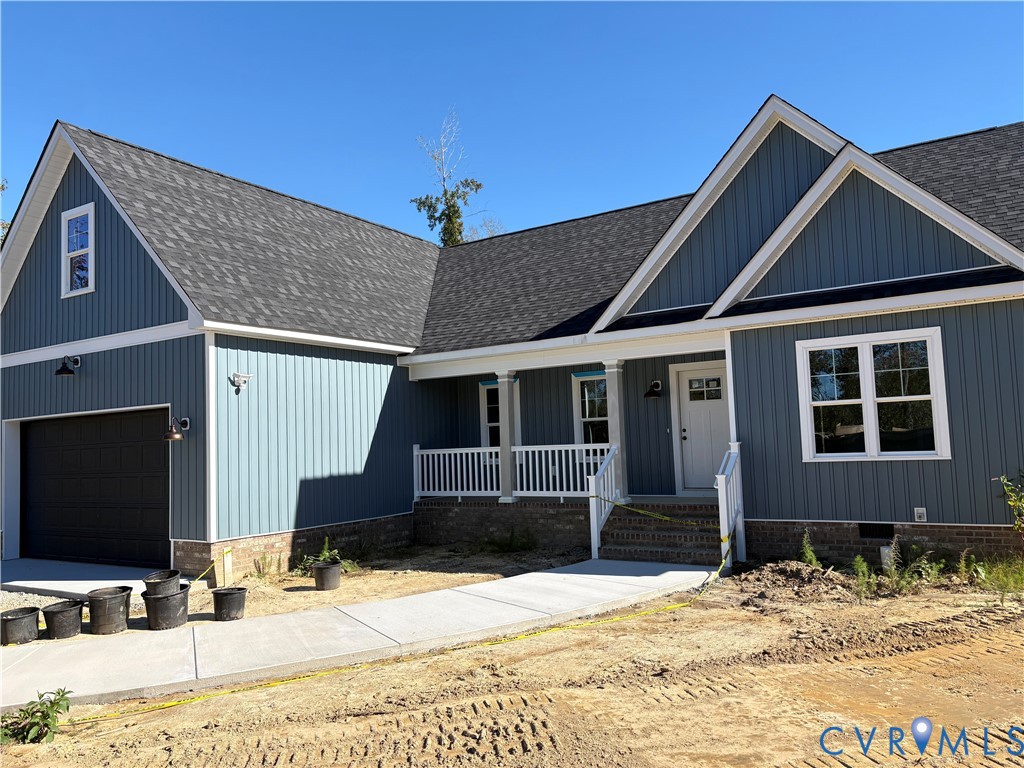 Board-and-batten siding exterior featuring a brick foundation, covered front porch with white railing, multi-gabled roofline, and attached garage Board-and-batten siding exterior featuring a brick foundation, covered front porch with white railing, multi-gabled roofline, and attached garage