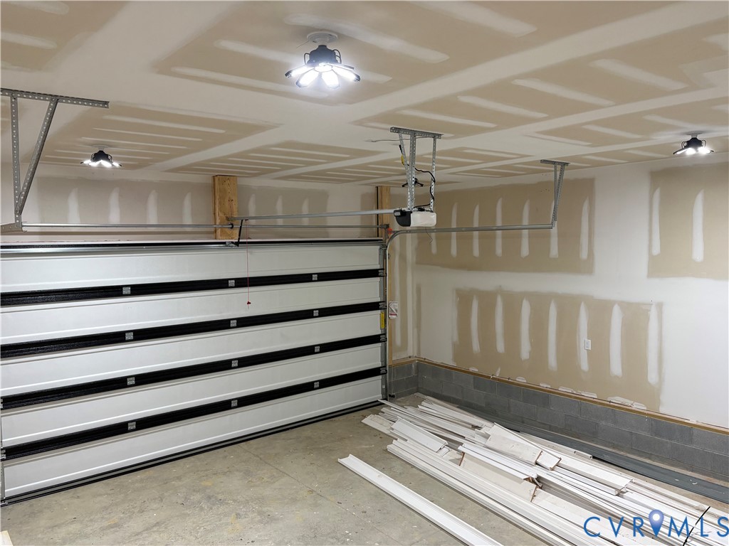 Attached two-car garage featuring a sectional overhead door, automated door opener, and multiple overhead LED light fixtures