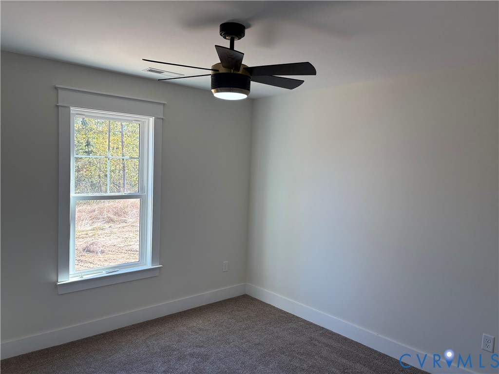Room featuring neutral wall tones, carpeted flooring, a single-hung window with a header trim, and a modern ceiling fan with an integrated light fixture