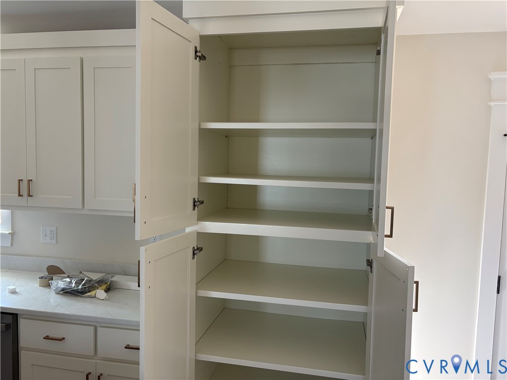 Floor-to-ceiling white cabinetry featuring shaker-style doors, adjustable shelving, and metallic hardware pulls Floor-to-ceiling white cabinetry featuring shaker-style doors, adjustable shelving, and metallic hardware pulls